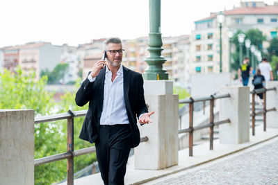 Businessman using mobile phone while walking outdoors