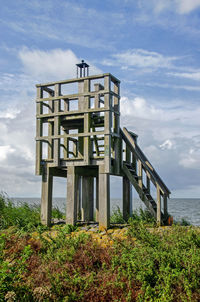 Little wooden observation tower under a sky with dramatic clouds on the harbour pier