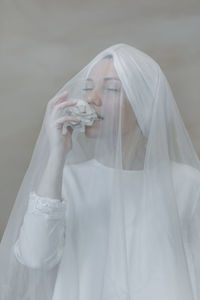 Bride biting paper ball against wall