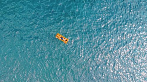 Aerial view of man on pool raft floating in sea