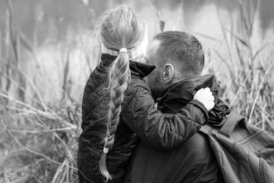 Father and daughter sitting by lake nature lanscape little girl hugging with dad fathers day concept