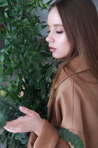 Beautiful woman with plants against wall