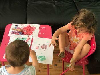 High angle view of siblings drawing on papers at home