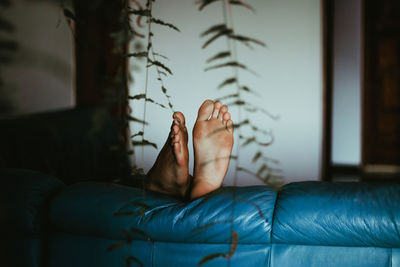 Midsection of woman lying on sofa at home