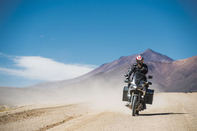 Man riding touring motorcycle on dusty road in bolivia