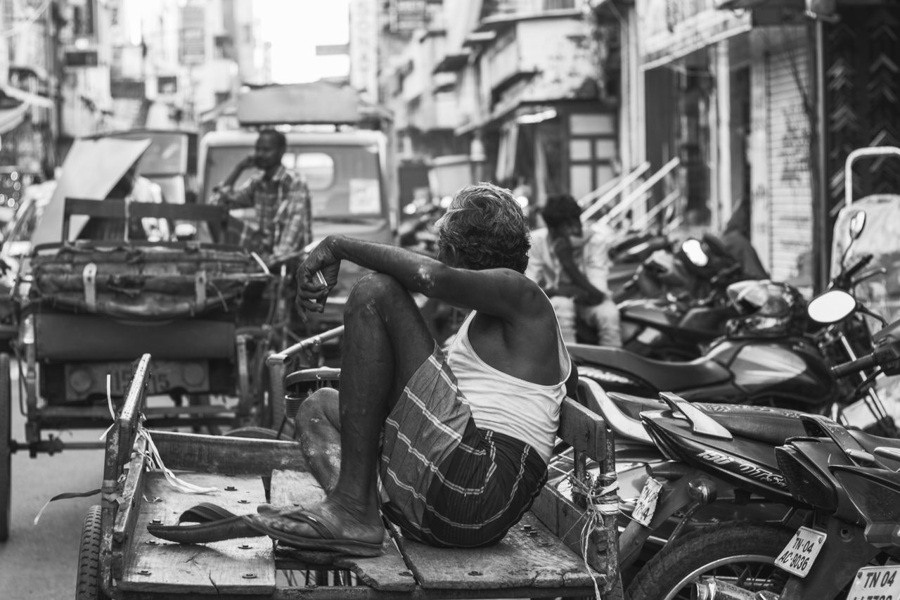 REAR VIEW OF A MAN SITTING IN A BUILDING