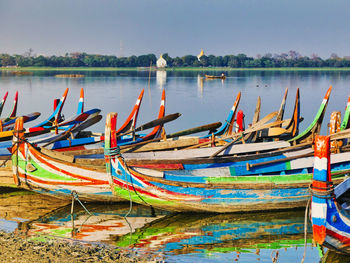 Fishing boats moored in lake against sky