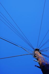 Low angle view of electricity pylon against clear blue sky