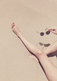 Low section of woman on sand at beach during sunny day