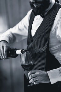 Midsection of bartendar pouring wine in glass