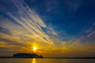 Scenic view of sea against dramatic sky during sunset