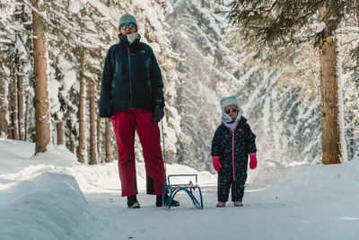 Mother and daughter on snow in woods