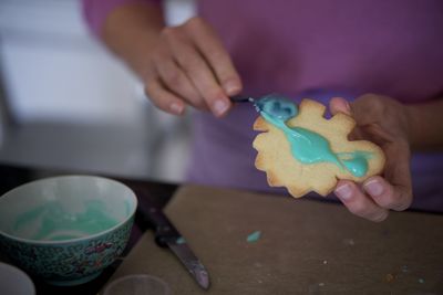 Midsection of woman holding cookies on table