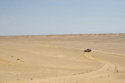 High angle view of off-road vehicle moving on desert against sky during sunny day