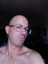 Portrait of shirtless man wearing eyeglasses at home