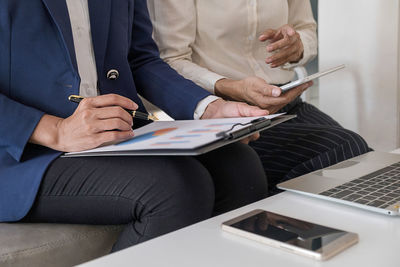 Midsection of businessman working with colleague at office