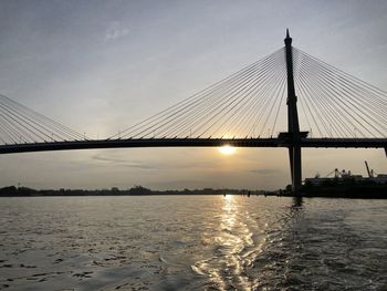 View of suspension bridge over river at sunset