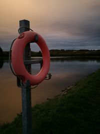 Close-up of life belt on lakeshore against sky during sunset