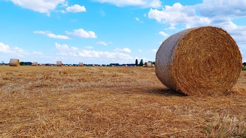 Hay bales on field against sky