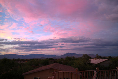 Houses against cloudy sky at sunset