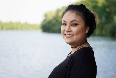 Portrait of smiling beautiful woman by lake