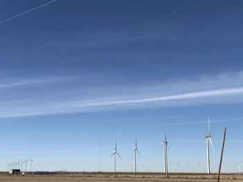 Wind turbines on field against sky