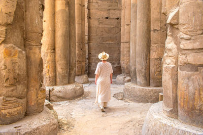 Woman with a hat walking backwards through the temple of luxor