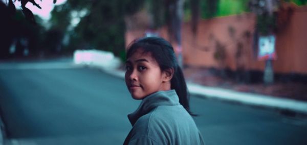 Portrait of teenage girl standing on street in city