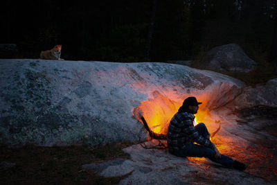 People sitting on rock by water at night