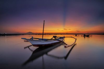 Silhouette boats moored on sea against sky during sunset