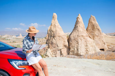 Rear view of woman standing on rock against sky