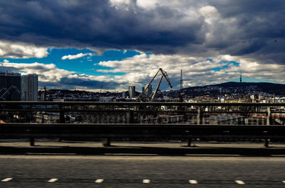 Bridge over city against cloudy sky