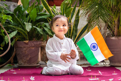 Cute toddler holding indian tricolor flag in traditional cloth with innocent facial expression