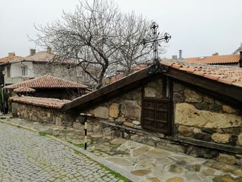 Bare tree and buildings against sky