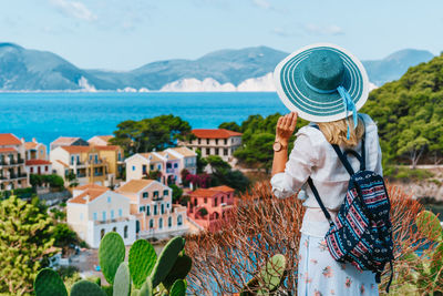 Rear view of woman looking at cityscape against sky