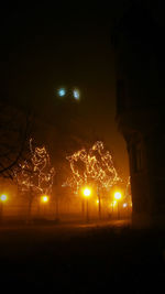 Illuminated street against sky at night