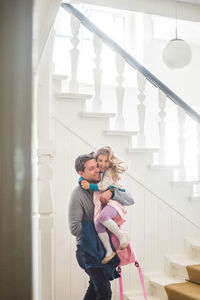 Cheerful father carrying daughter while leaving for school