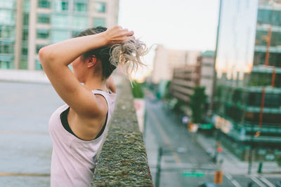 Side view of woman tying hair on building terrace