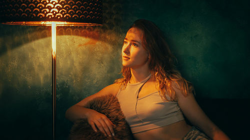 Portrait of young woman standing against wall