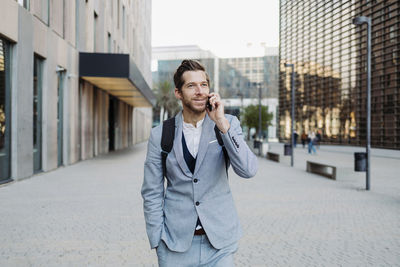 Male entrepreneur talking on mobile phone while standing on road in city