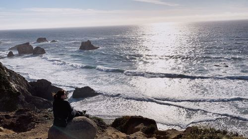 Rear view of man looking at sea shore against sky