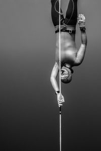 Low angle view of person holding rope against pole
