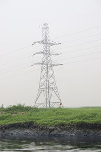 Low angle view of electricity pylon on field against clear sky