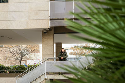 Bearded hipster man relaxing on stairs in a building complex