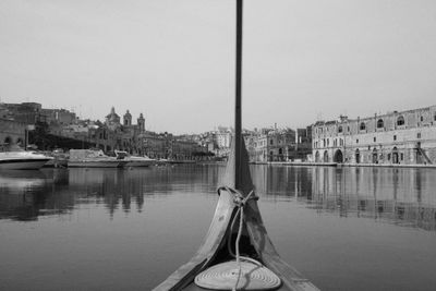 Sailboats moored in city against clear sky