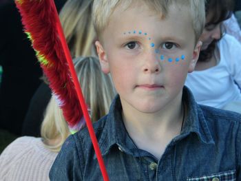 Close-up portrait of cute boy with blue paint spots on face