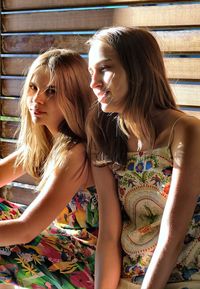Sisters sitting together against wooden wall