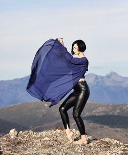 Full length portrait of young woman against mountains