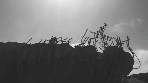 Low angle view of silhouette telephone on roof against sky