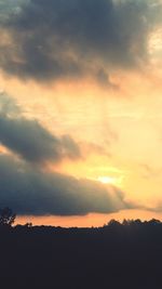 Silhouette landscape against cloudy sky